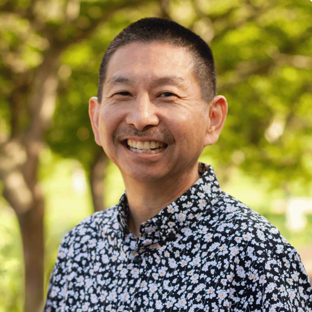 Roger Higa smiling outdoors